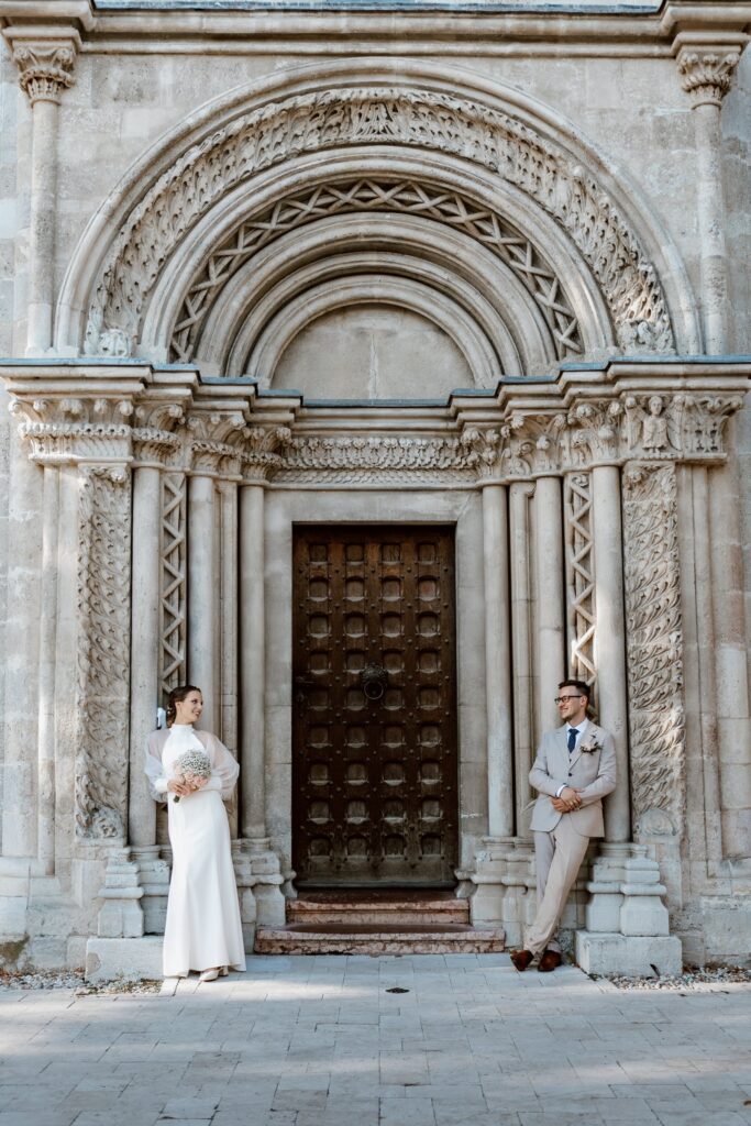 Az ifjú pár a román kori templom kapuja előtt